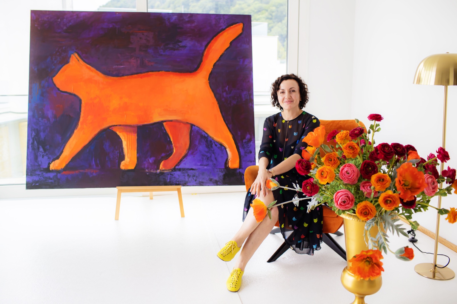 Curator beside orange cat painting and floral arrangement at Vienna art exhibition — Best Alex Shots