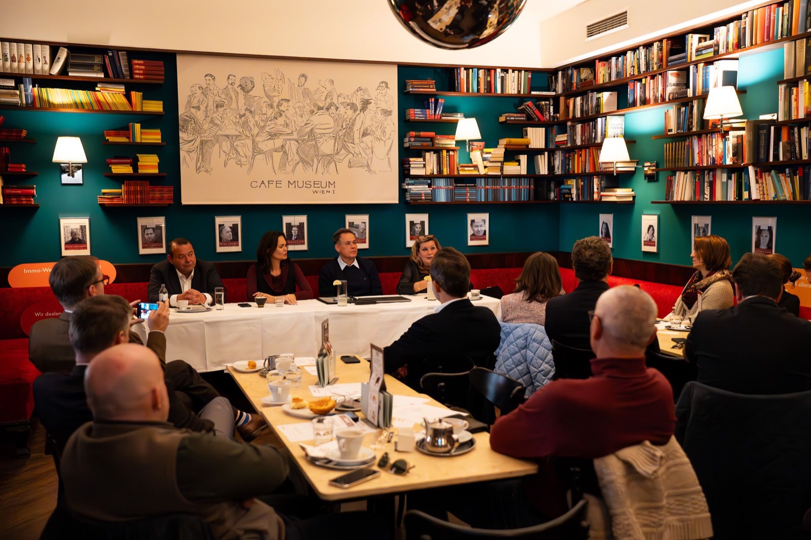 Panel discussion at Café Museum Vienna with library backdrop — event photography by Best Alex Shots