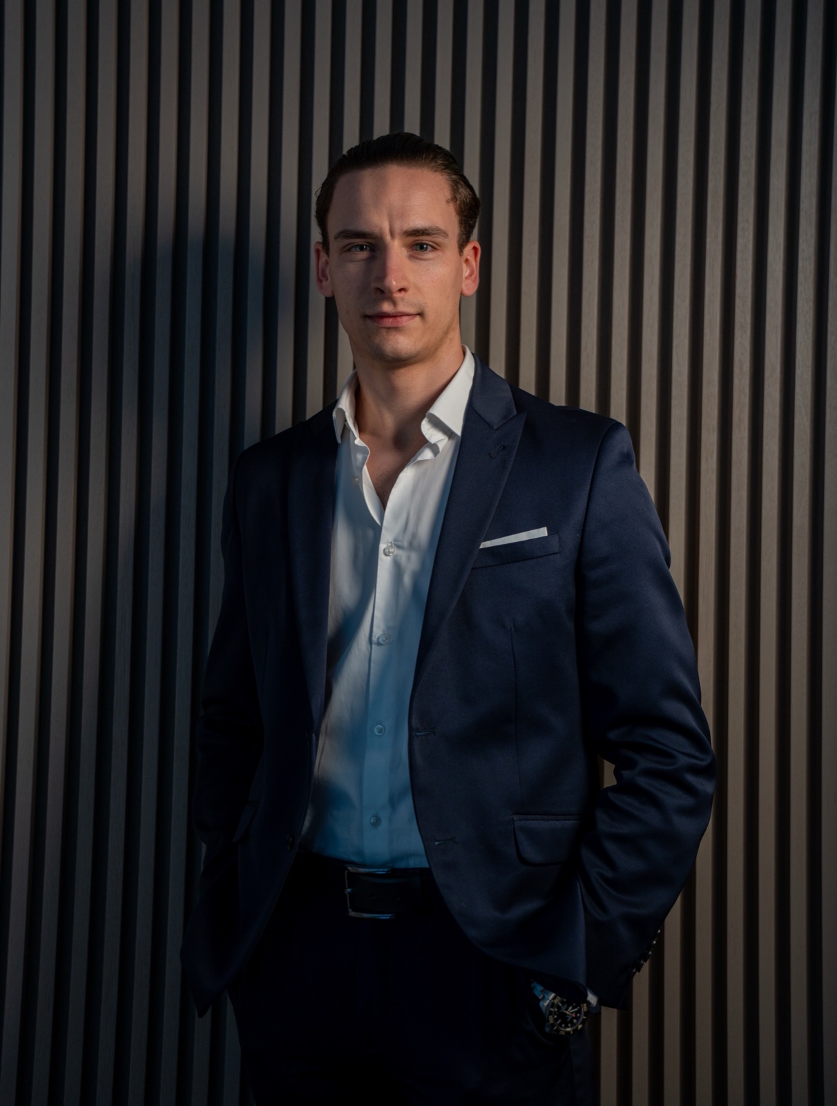 Young man in navy suit against vertical wood panelling — moody corporate portrait by Best Alex Shots, Vienna