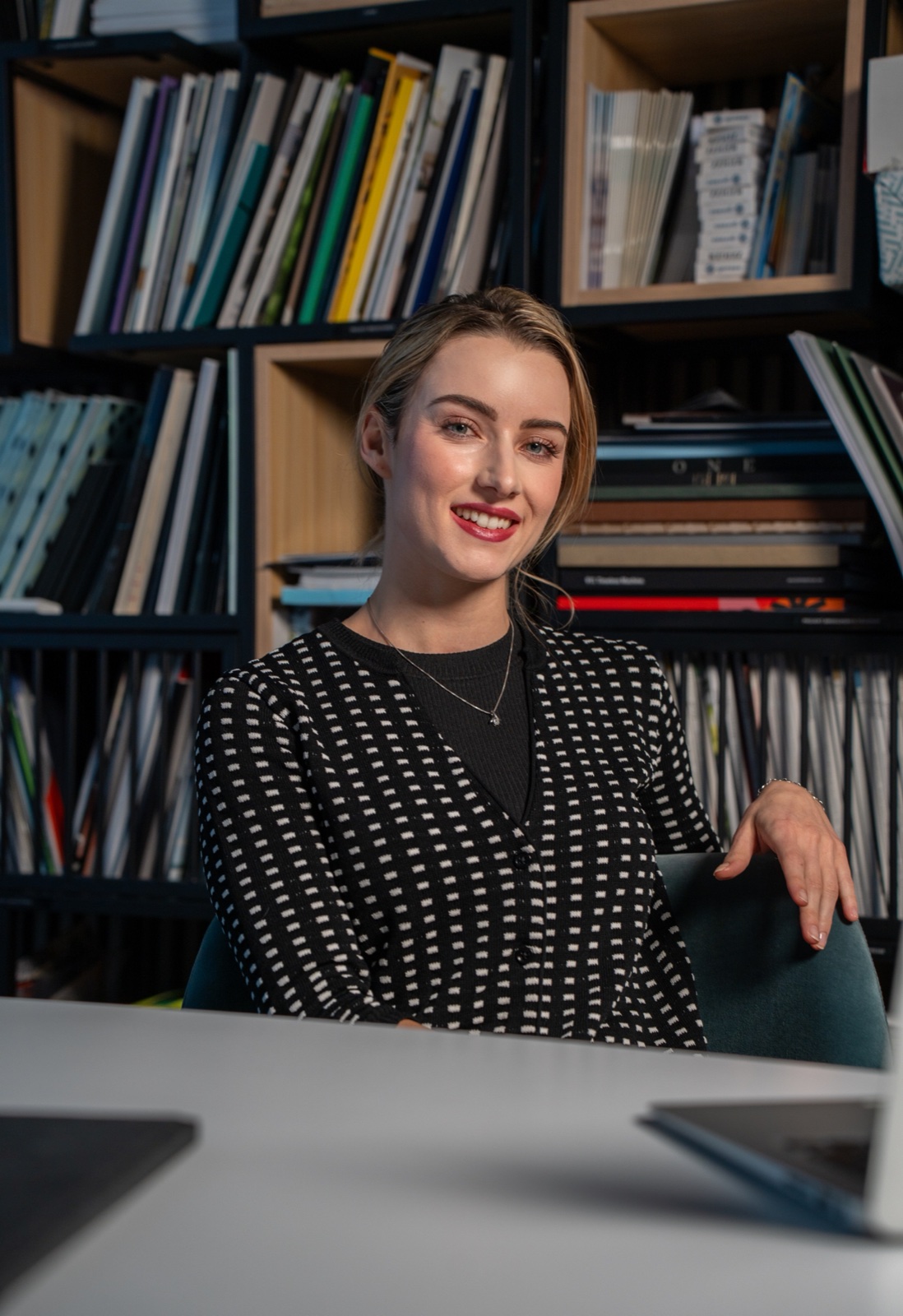 Smiling team member in patterned cardigan in office with bookshelves — corporate portrait by Best Alex Shots, Vienna