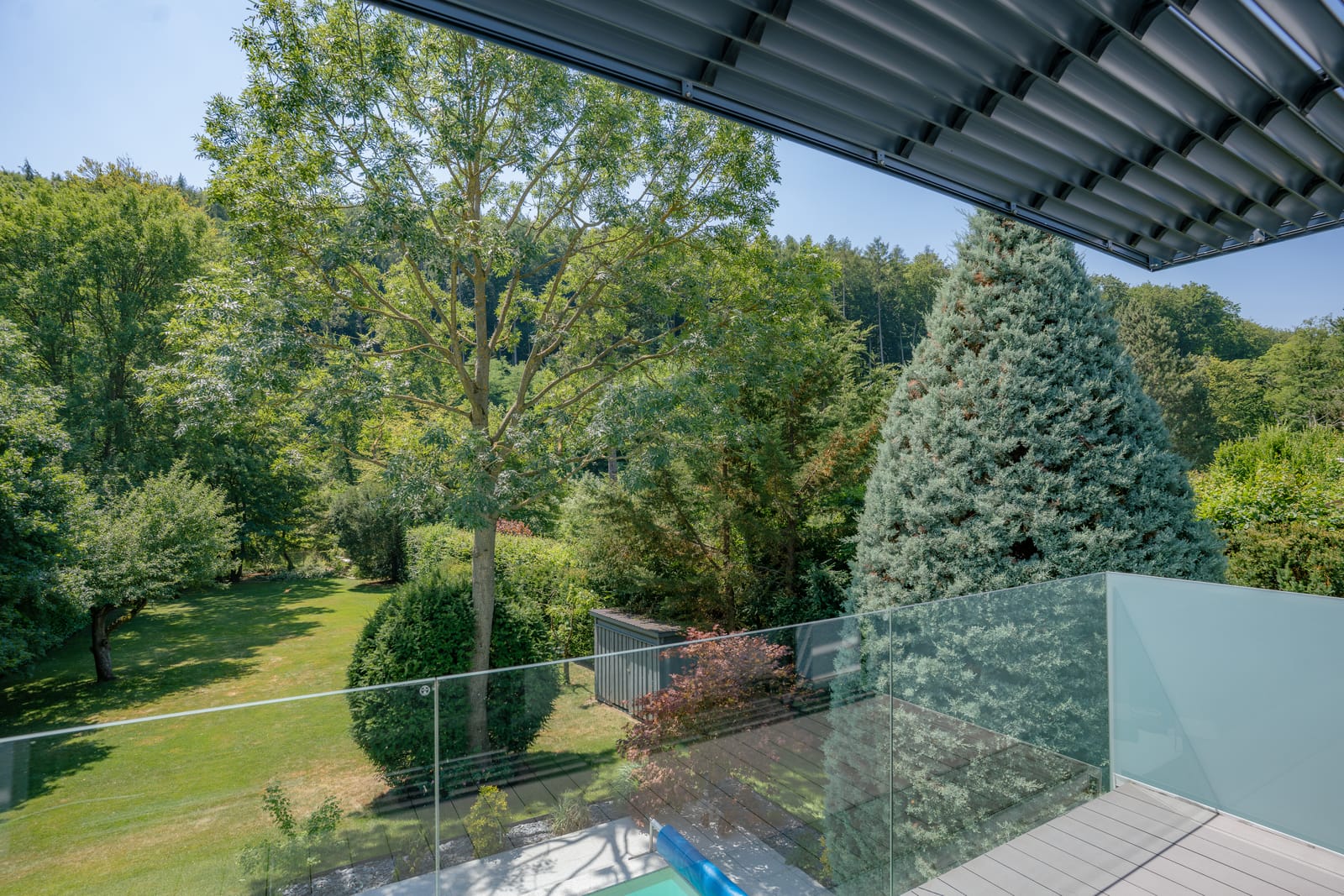 View from a contemporary villa terrace with glass balustrade over a green garden and forest in summer, Vienna — Best Alex Shots real estate photography